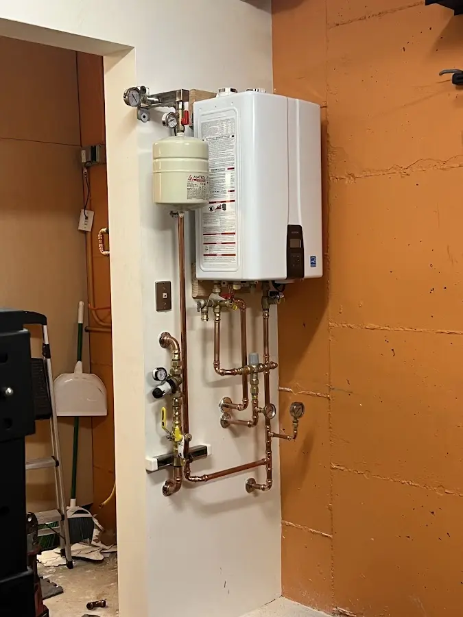 Plumbing technician inspecting water heater connections in Forest Lake